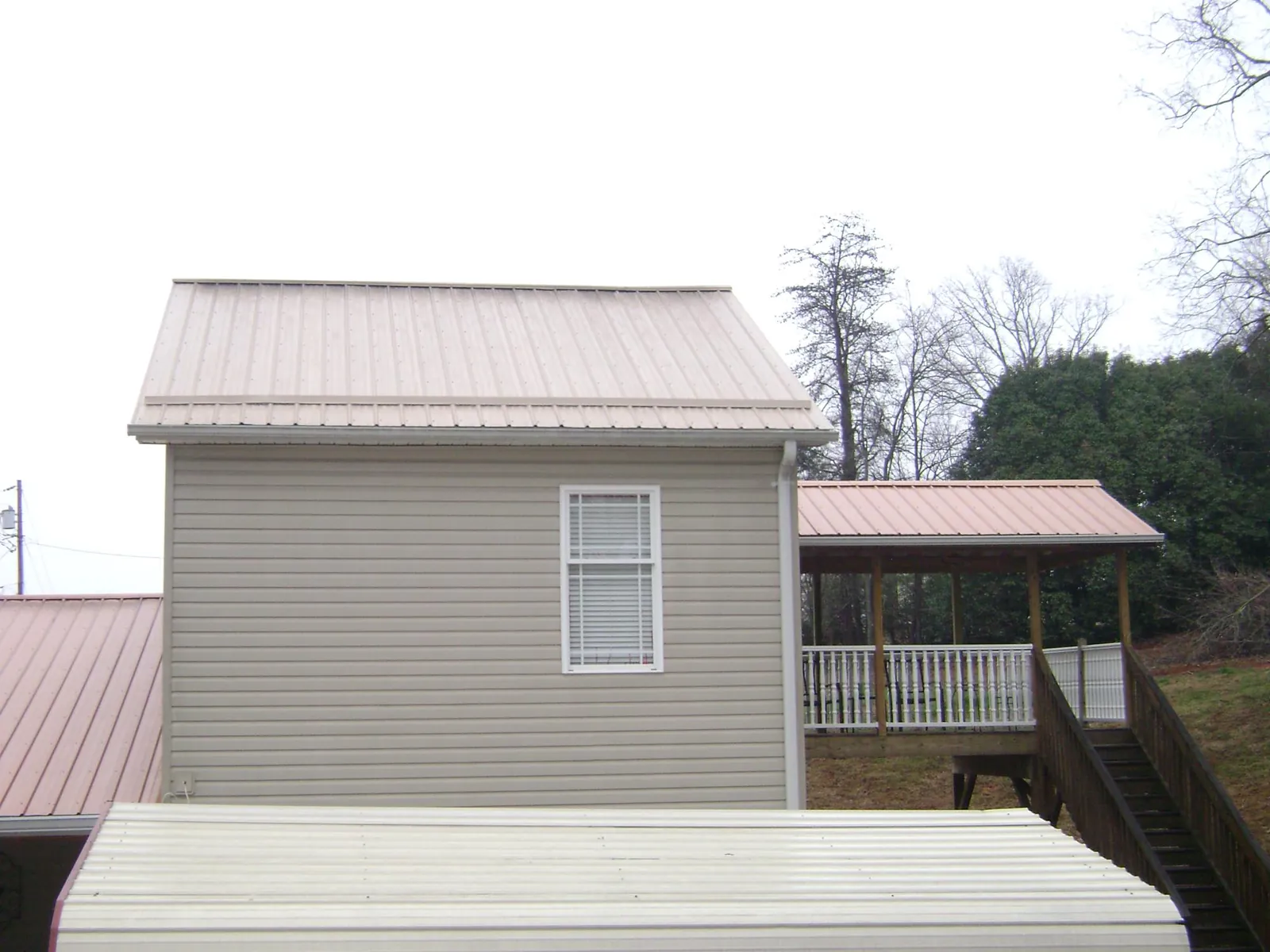 Tan metal roofs on a two story addition and attached porch, from a Roof Replacement job in Neah Bay