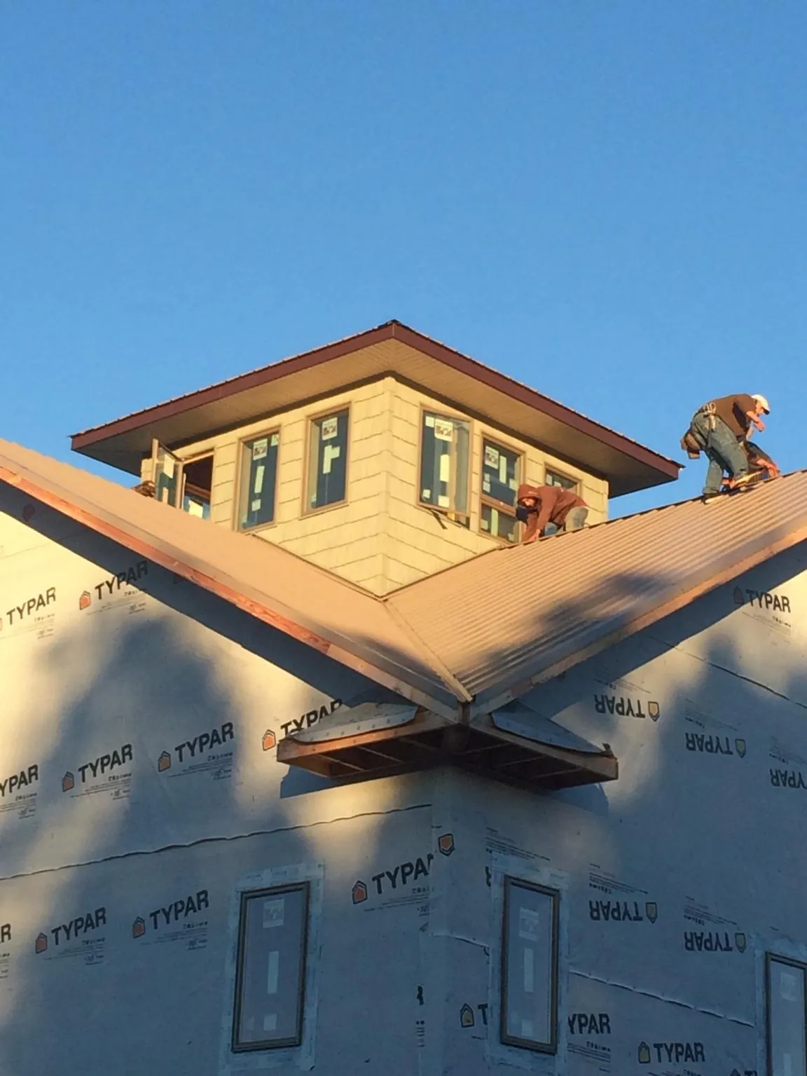 Roofers working around a rooftop cupola on a new metal roof at sunset — Roof Waterproofing in Neah Bay by Roofing Brothers